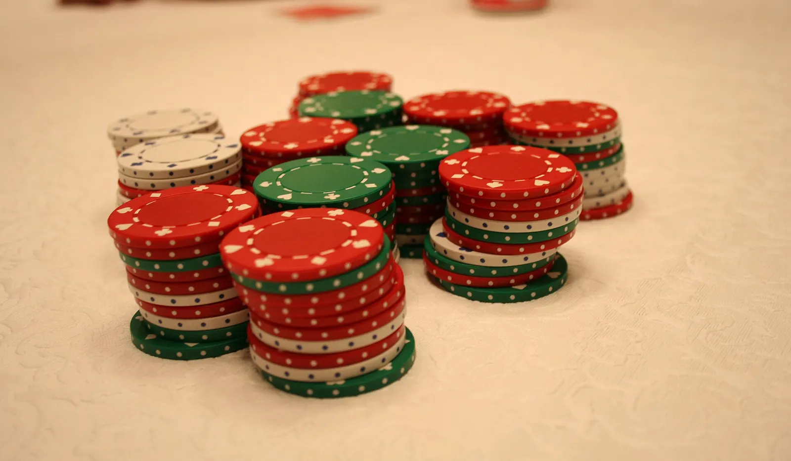 Stacks of red, green and white poker chips on a tablecloth at the end of a home game.